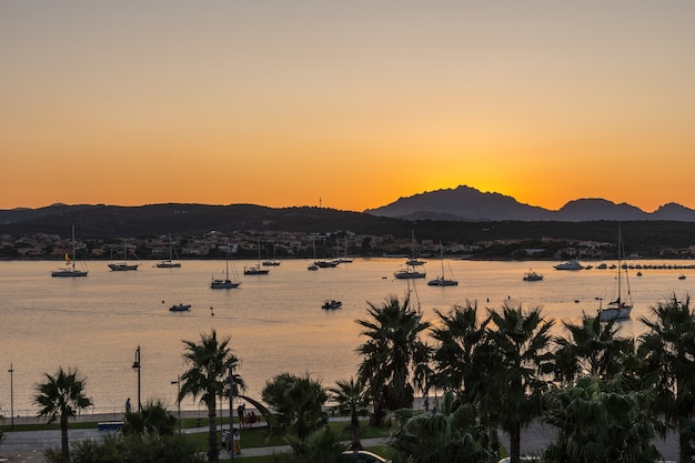 Nahaufnahme des Sonnenuntergangs gegen Berge und Meer mit horizontaler Ausrichtung der Yachten