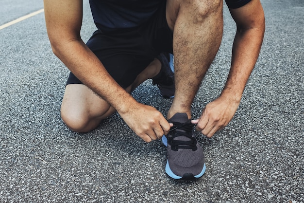 Nahaufnahme des Sportlers Laufschuhe bindend