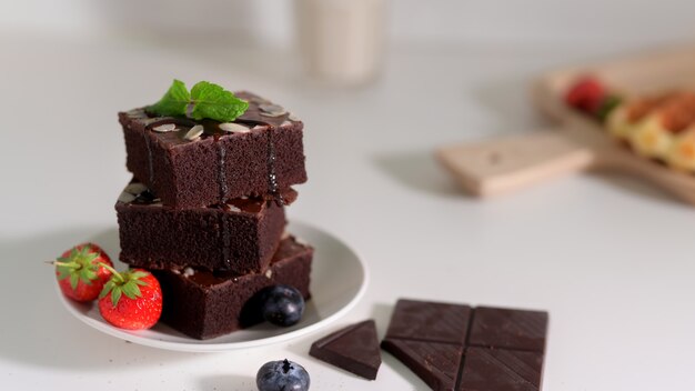 Nahaufnahme des Stapels Schokoladen-Brownies auf weißem Teller mit Minzblatt oben