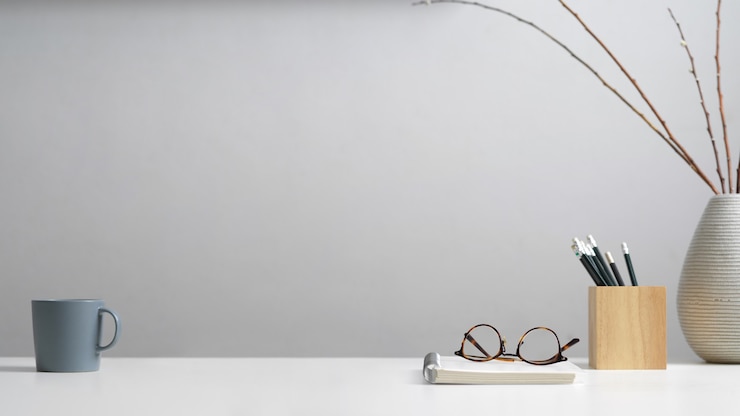 Foto nahaufnahme des studientisches mit briefpapier, brille, notizbuch, becher, dekoration und kopierraum im heimbüro