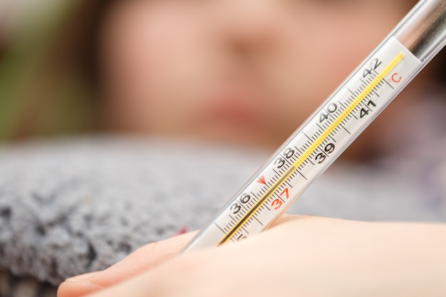 Nahaufnahme des Thermometers, das Kind misst die Temperatur, Erkältungen und Grippe zu Hause hohes Fieber, der Arzt überprüft den Patienten, die Temperatur ist achtunddreißig am Thermometer