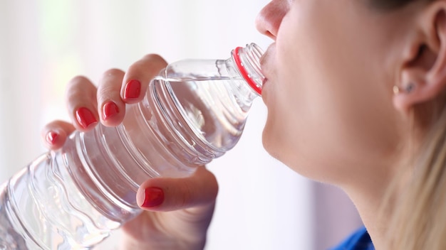 Nahaufnahme des Trinkwassers der jungen Frau von der Plastikflasche