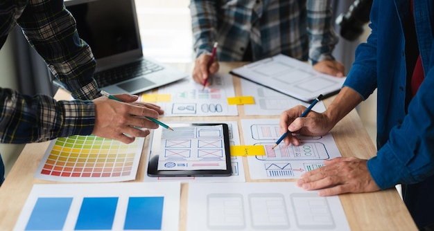 Nahaufnahme des UI-Entwicklerteams beim Brainstorming für ihr Projekt mit Laptop, Smartphone und digitalem Tablet Kreative Agentur für digitale Entwicklung