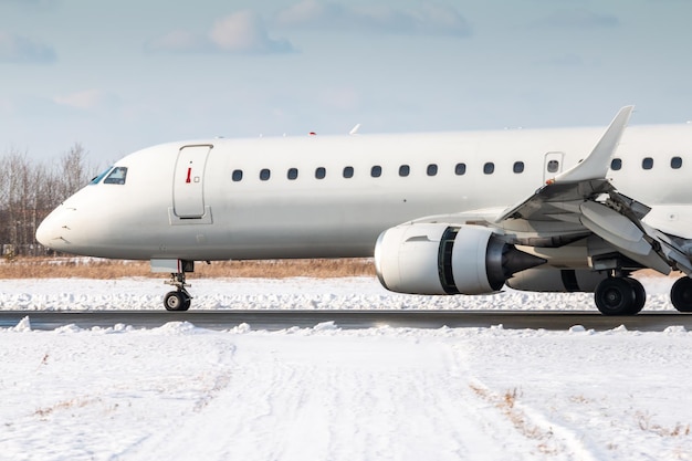 Nahaufnahme des weißen Passagierflugzeugs auf der Start- und Landebahn eines Winterflughafens