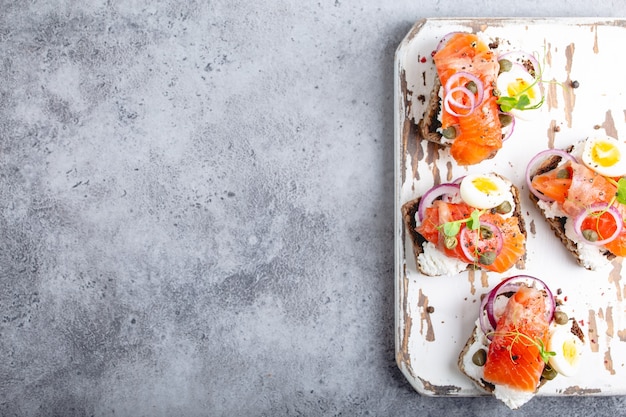 Nahaufnahme Draufsicht auf Sandwich mit Brot Käse Lachs Ei Schneidebrett Beton Hintergrund