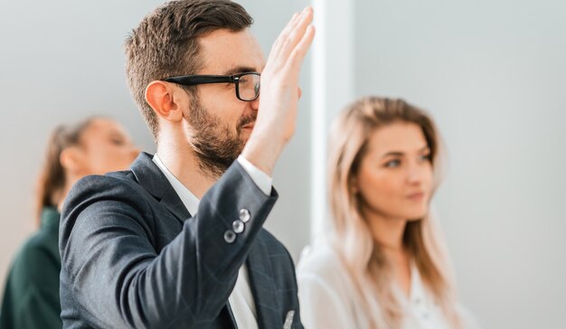 Nahaufnahme. Ein junger Geschäftsmann stellt während eines Business-Seminars eine Frage. Foto mit Textfreiraum