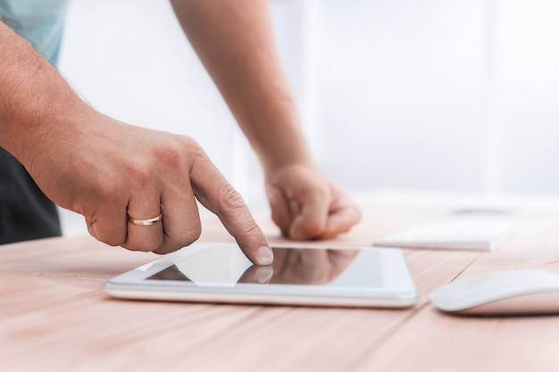 Nahaufnahme. Ein junger Mann benutzt ein digitales Tablet im Büro. Mensch und Technik