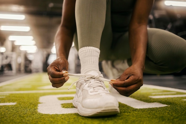 Nahaufnahme einer afroamerikanischen Sportlerin mit 39 Händen, die Schnürsenkel an einem Sneaker im Fitnessstudio binden