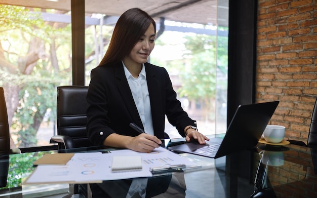 Nahaufnahme einer asiatischen Geschäftsfrau, die während der Arbeit im Büro einen Laptop verwendet und tippt