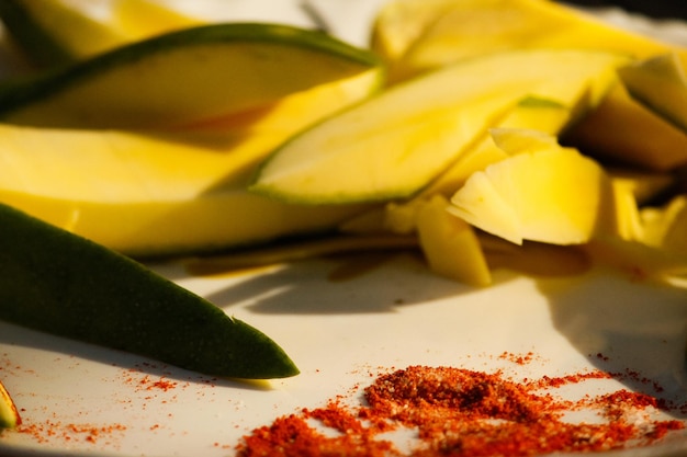 Nahaufnahme einer aufgeschnittenen Mango neben Tajin