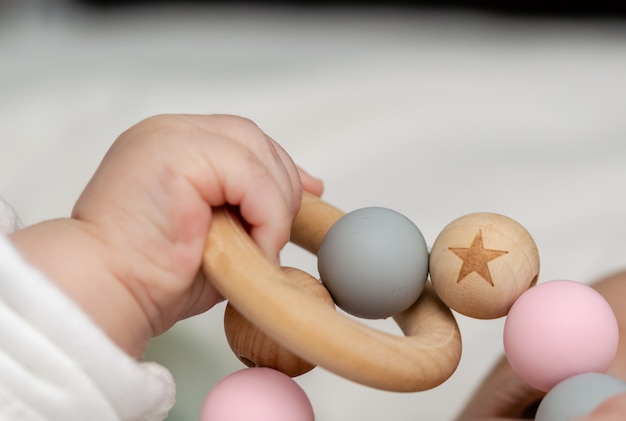 Nahaufnahme einer Babyhand, spielend mit einem hölzernen Spielzeug.