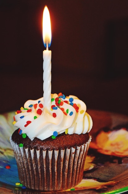 Nahaufnahme einer beleuchteten Kerze auf einem Cupcake