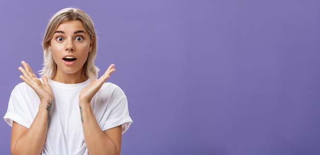 Nahaufnahme einer bezauberten und beeindruckten gut aussehenden kaukasischen Freundin mit blonden Haaren und Tätowierungen