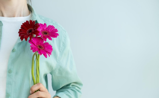 Nahaufnahme einer Blume in der Hand eines Mädchens, das vor einem hellen Hintergrund steht Platz für Text