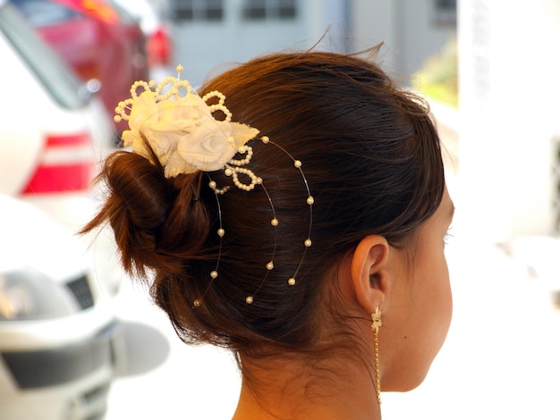 Nahaufnahme einer Braut, die Blumen auf einem Haarbrötchen trägt