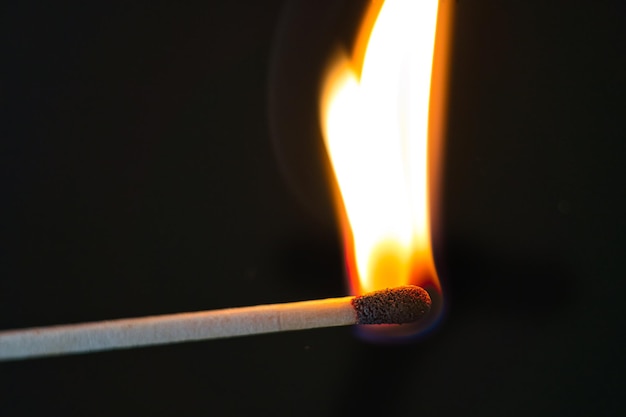Nahaufnahme einer brennenden Kerze vor schwarzem Hintergrund