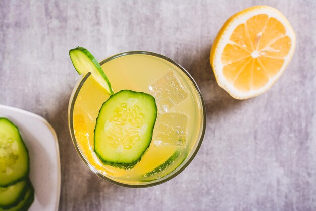 Nahaufnahme einer erfrischenden Limonade mit Zitronengurke und Eis in einem Glas auf der Tischplatte