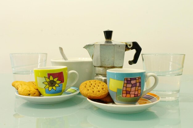 Nahaufnahme einer Espresso-Maschine mit Tassen und Kekse auf dem Tisch