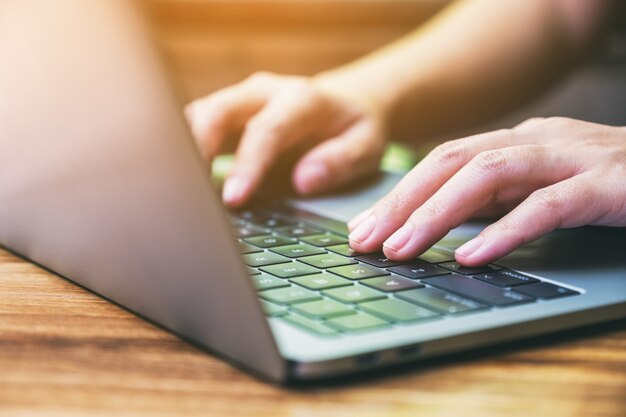 Nahaufnahme einer Frau, die auf dem Laptop auf dem Tisch arbeitet und tippt