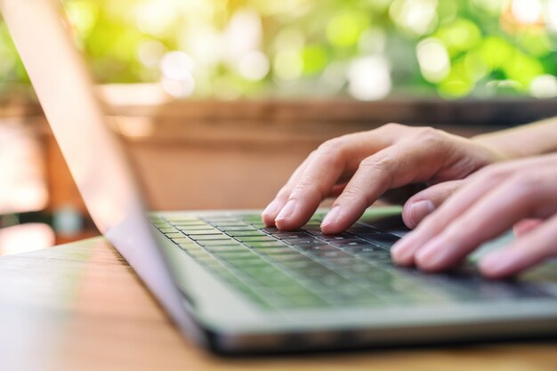 Nahaufnahme einer Frau, die auf dem Laptop auf dem Tisch arbeitet und tippt