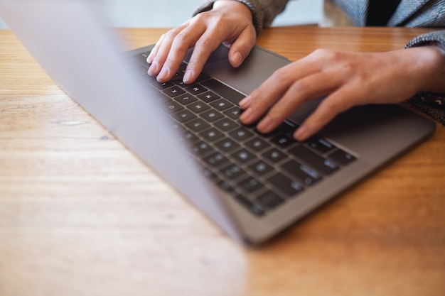 Nahaufnahme einer Frau, die auf der Tastatur eines Laptops auf dem Tisch arbeitet und tippt