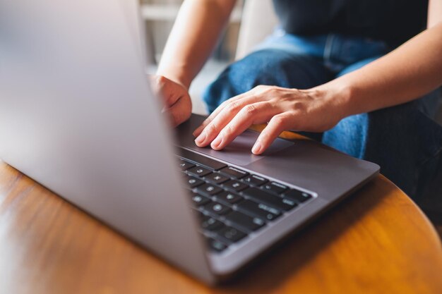 Nahaufnahme einer Frau, die auf der Tastatur eines Laptops auf dem Tisch arbeitet und tippt