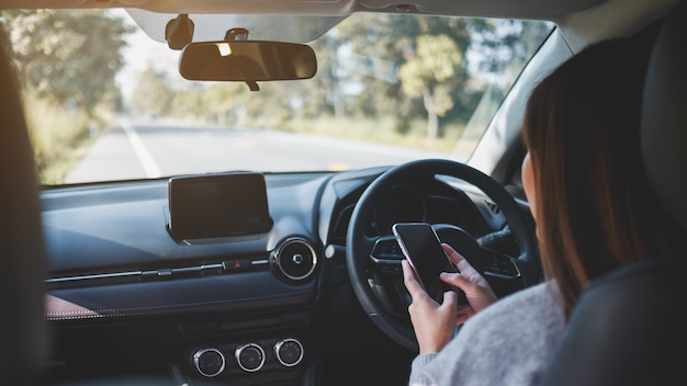 Nahaufnahme einer Frau, die beim Autofahren Handy benutzt