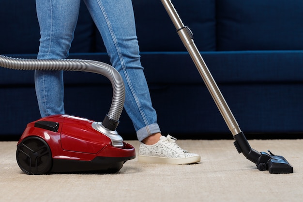 Nahaufnahme einer Frau, die den Teppich staubsaugt