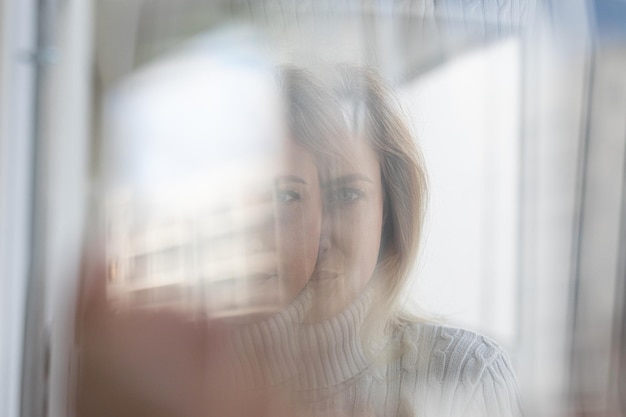 Nahaufnahme einer Frau, die durch das Fenster schaut