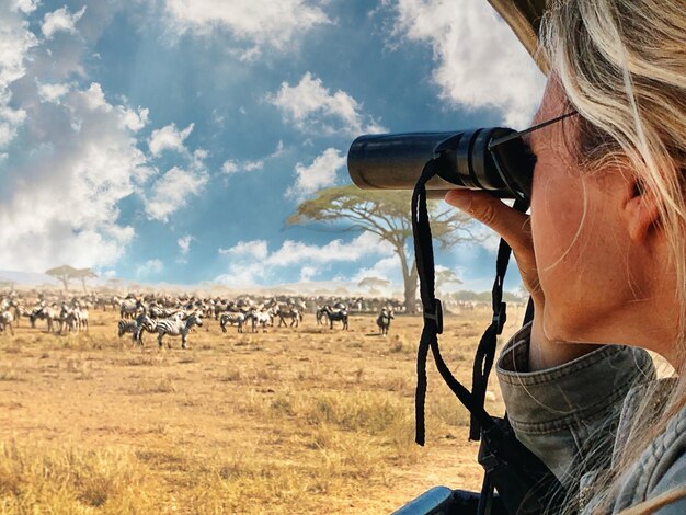 Foto nahaufnahme einer frau, die durch ein fernglas auf zebras im serengeti-nationalpark schaut