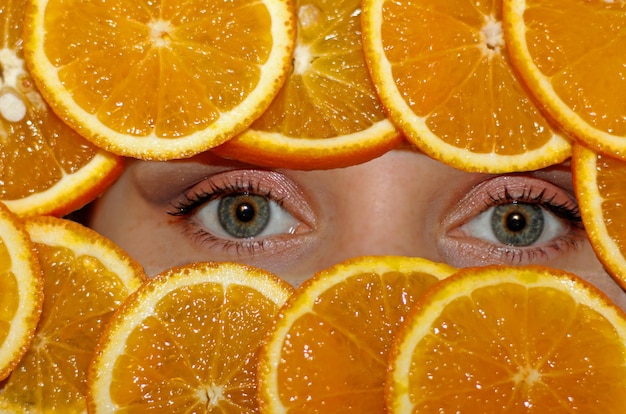 Foto nahaufnahme einer frau, die durch orangenscheiben schaut