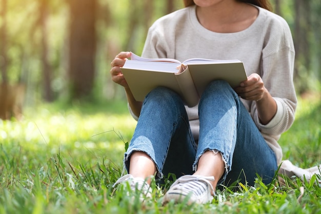 Nahaufnahme einer Frau, die ein Buch liest, während sie im Park sitzt