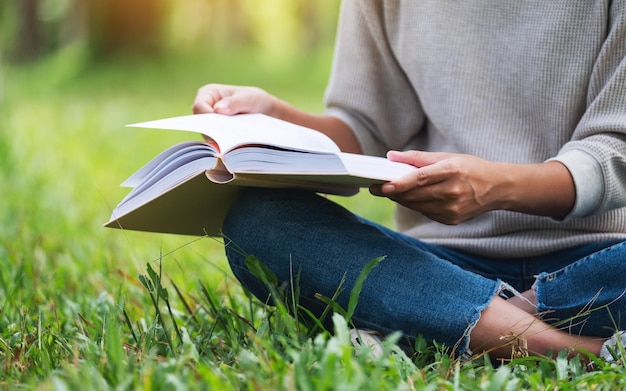 Nahaufnahme einer Frau, die ein Buch liest, während sie im Park sitzt