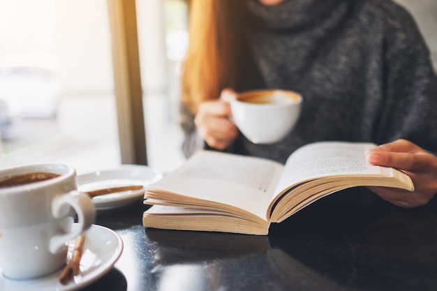 Nahaufnahme einer Frau, die ein Buch liest, während sie Kaffee im Café trinkt