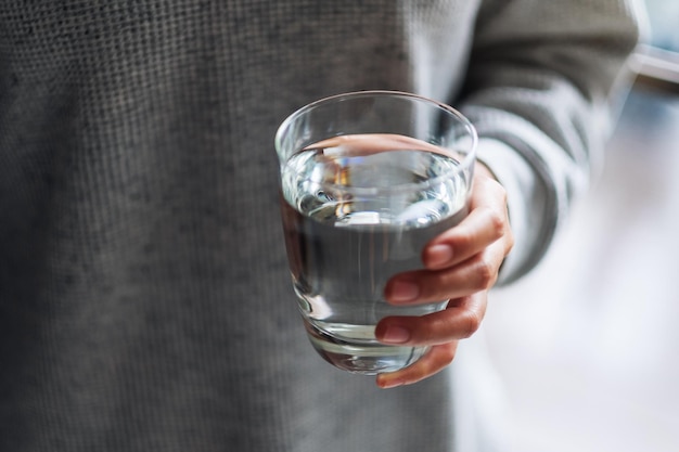 Nahaufnahme einer Frau, die ein Glas reines Wasser hält