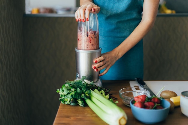 Nahaufnahme einer Frau, die einen fruchtigen Sommer-Pink-Smoothie zubereitet