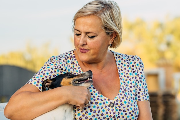 Nahaufnahme einer Frau, die einen kleinen alten Hund im Freien umarmt