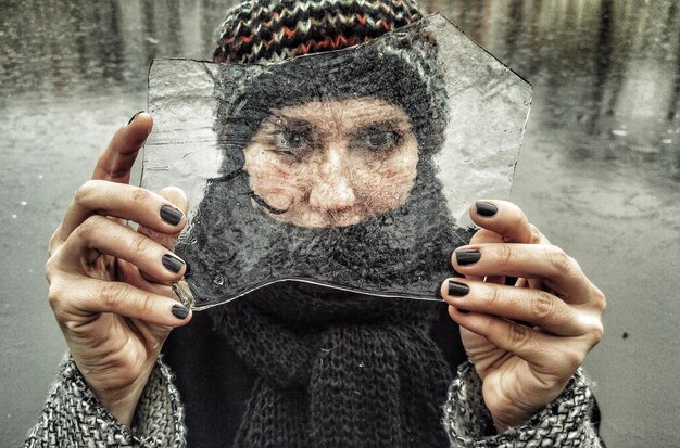 Nahaufnahme einer Frau, die Eis gegen einen gefrorenen See hält