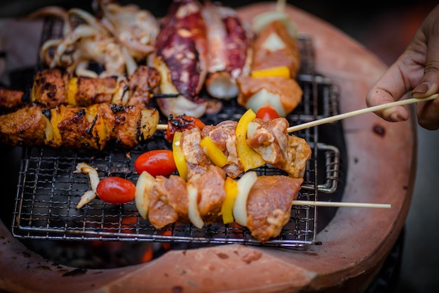 Nahaufnahme einer Frau, die Fleisch auf dem Grill hält