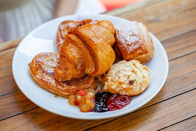 Nahaufnahme einer Frau, die frische Brötchen isst, die im Café im Freien frühstücken, im Hotel?