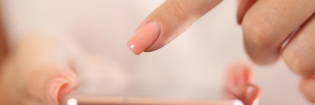 Nahaufnahme einer Frau, die ihr Mobiltelefon mit einem Finger über dem Bildschirm hält. Scrollen Sie mit dem weiblichen Finger des Telefons