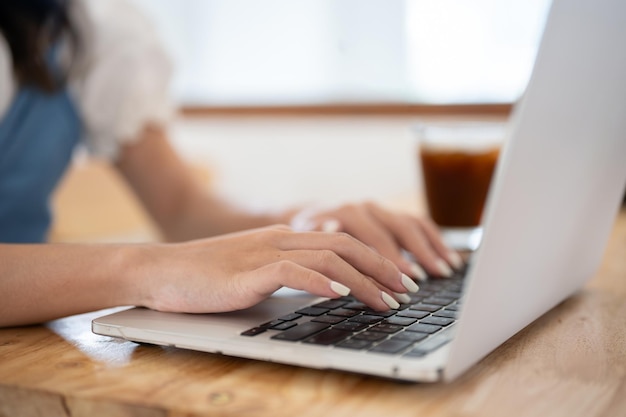 Nahaufnahme einer Frau, die ihren Laptop an einem Tisch in einem Café benutzt