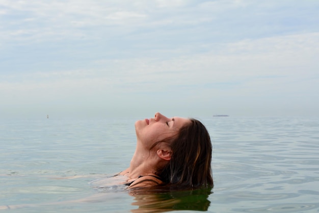 Nahaufnahme einer Frau, die im Meer gegen den Himmel schwimmt