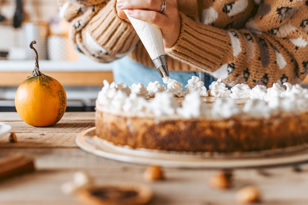 Foto nahaufnahme einer frau, die kuchen backt, schlagsahne und kürbiskuchen