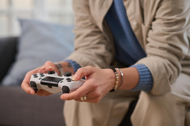 Foto nahaufnahme einer frau, die mit dem joystick ein spiel spielt, während sie zu hause auf dem sofa sitzt