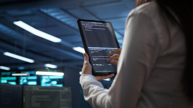 Nahaufnahme einer Frau, die mit einem Tablet Wartung im Serverraum durchführt
