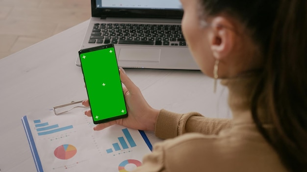 Nahaufnahme einer Frau, die mit grünem Bildschirm und Chroma-Key auf das Telefon schaut. Erwachsener, der ein Mobiltelefon mit isolierter Mockup-Vorlage und Hintergrund hält und Chroma-Key auf dem Telefondisplay verwendet.