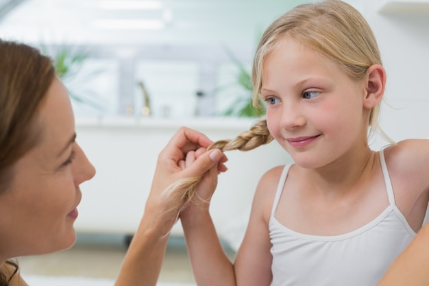 Nahaufnahme einer Frau, die nettes Haar der kleinen Mädchen justiert