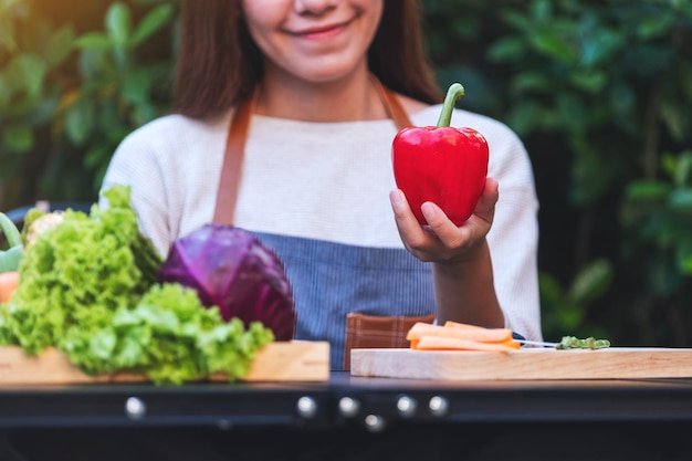 Nahaufnahme einer Frau, die Paprika aus einem gemischten Gemüse in einem Holztablett auswählt