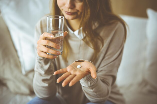 Nahaufnahme einer Frau, die Pillen hält, um Medikamente einzunehmen, Kopfschmerzen, Bluthochdruck oder Cholesterinspiegel zu heilen, um Schmerzmittel zu beseitigen. Bleiben Sie zu Hause während der Coronavirus-Pandemie und selbst i